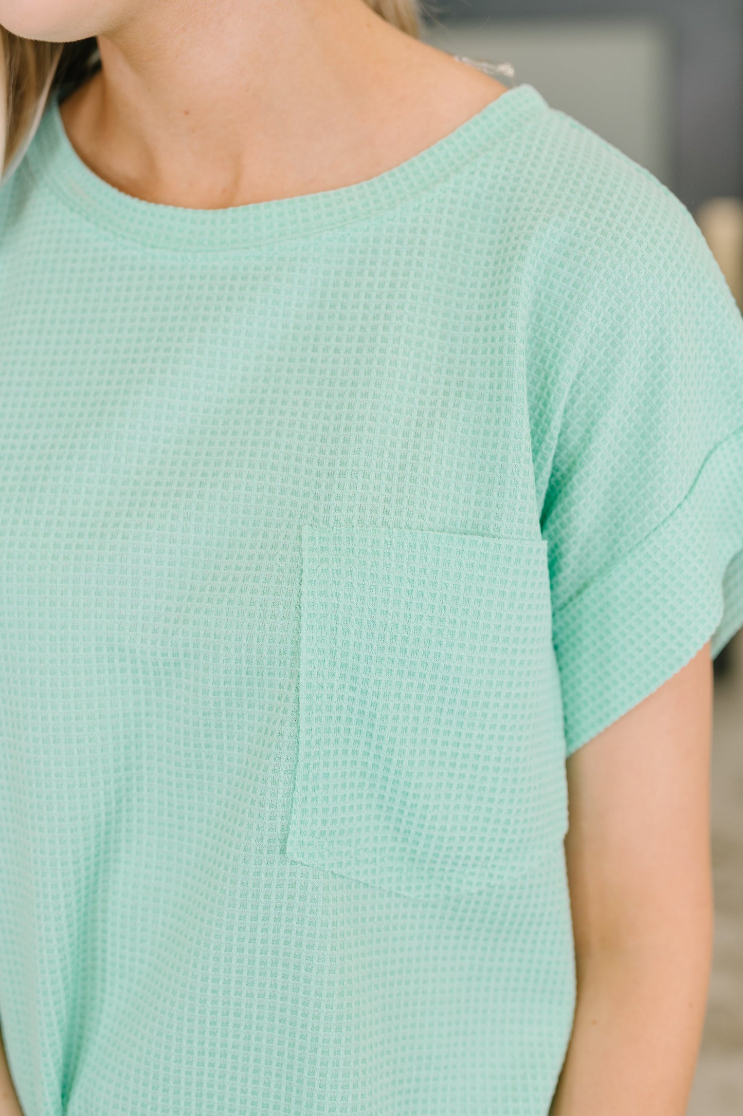 Person wearing a light green textured dress with a blurred background