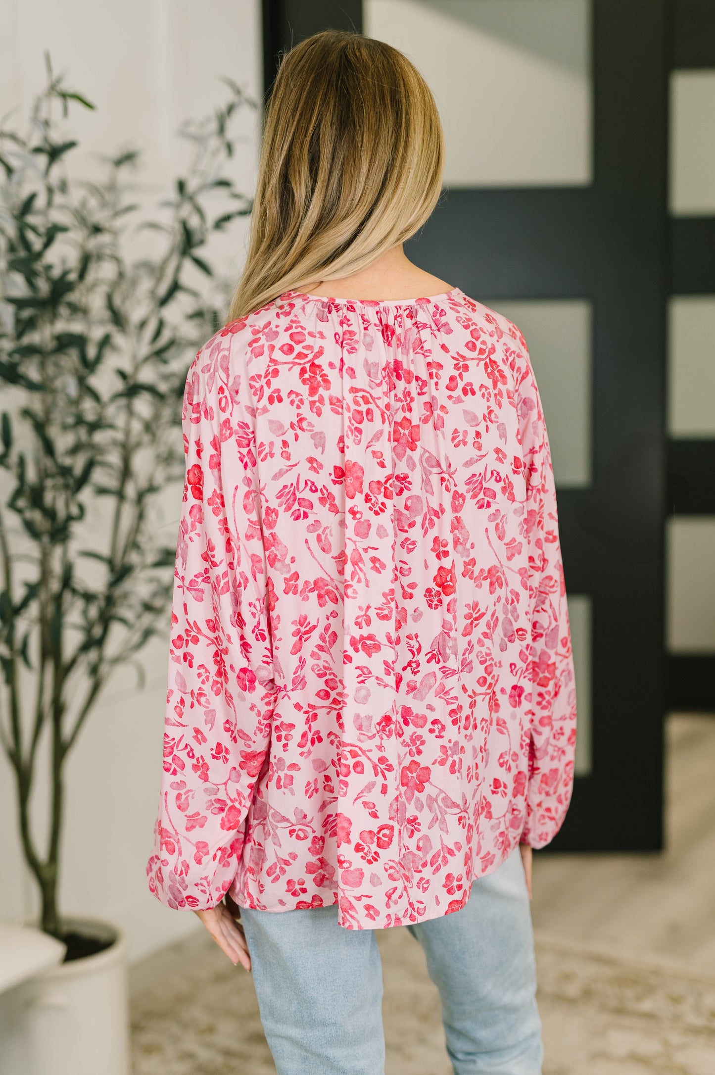 Person wearing a pink floral blouse with a blurred background