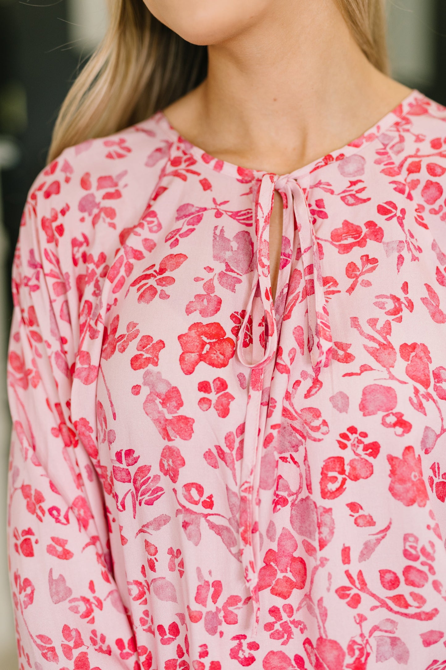 Close-up of a person wearing a pink floral blouse with a blurred background