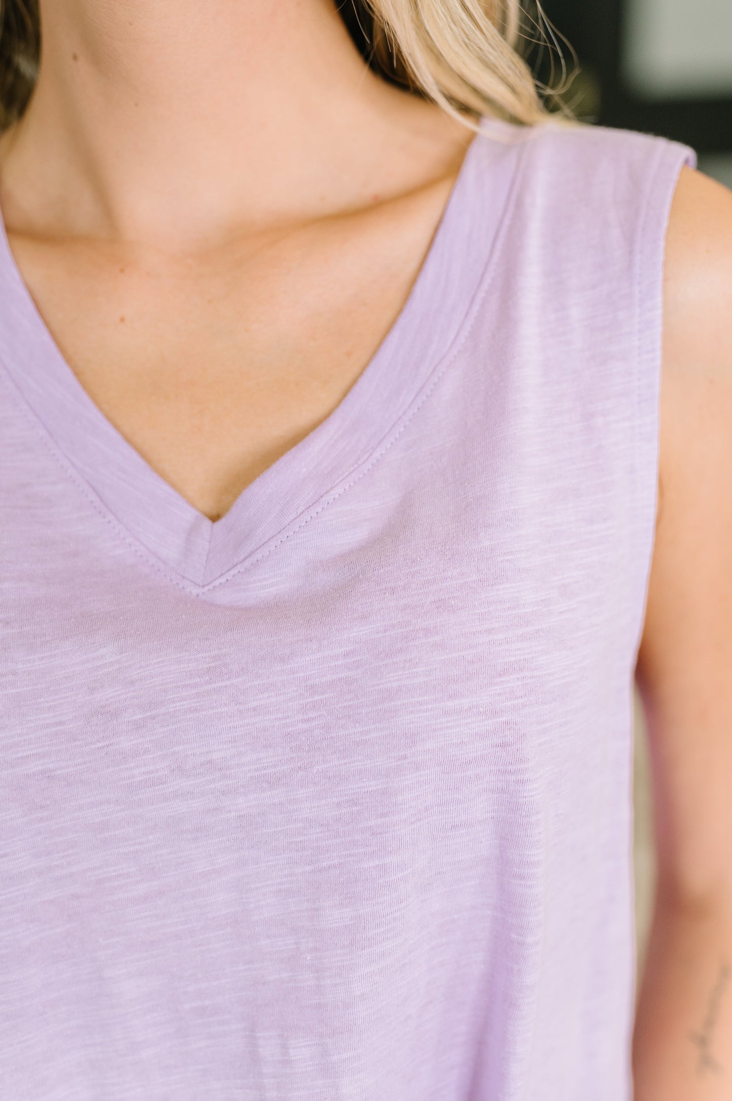 Close-up of a person wearing a light purple sleeveless top.