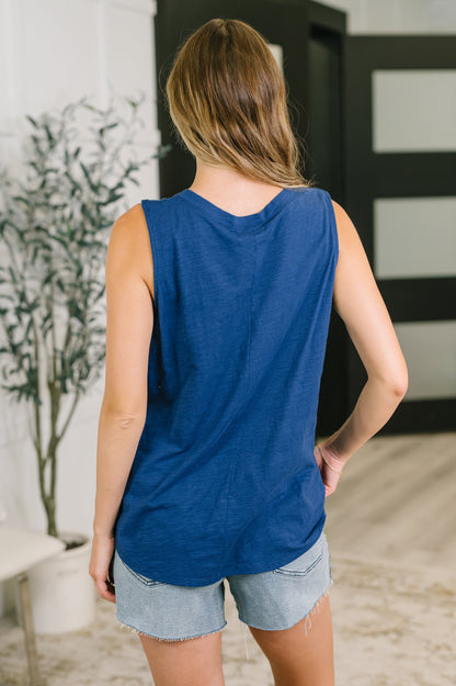 Woman wearing a blue sleeveless top and denim shorts in an indoor setting.