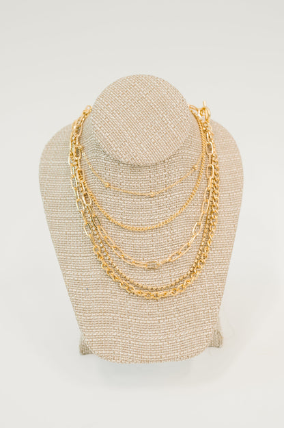 Gold chain necklace on a beige mannequin bust against a white background