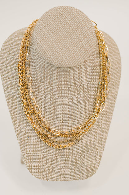 Gold chain necklace on a mannequin bust against a plain background