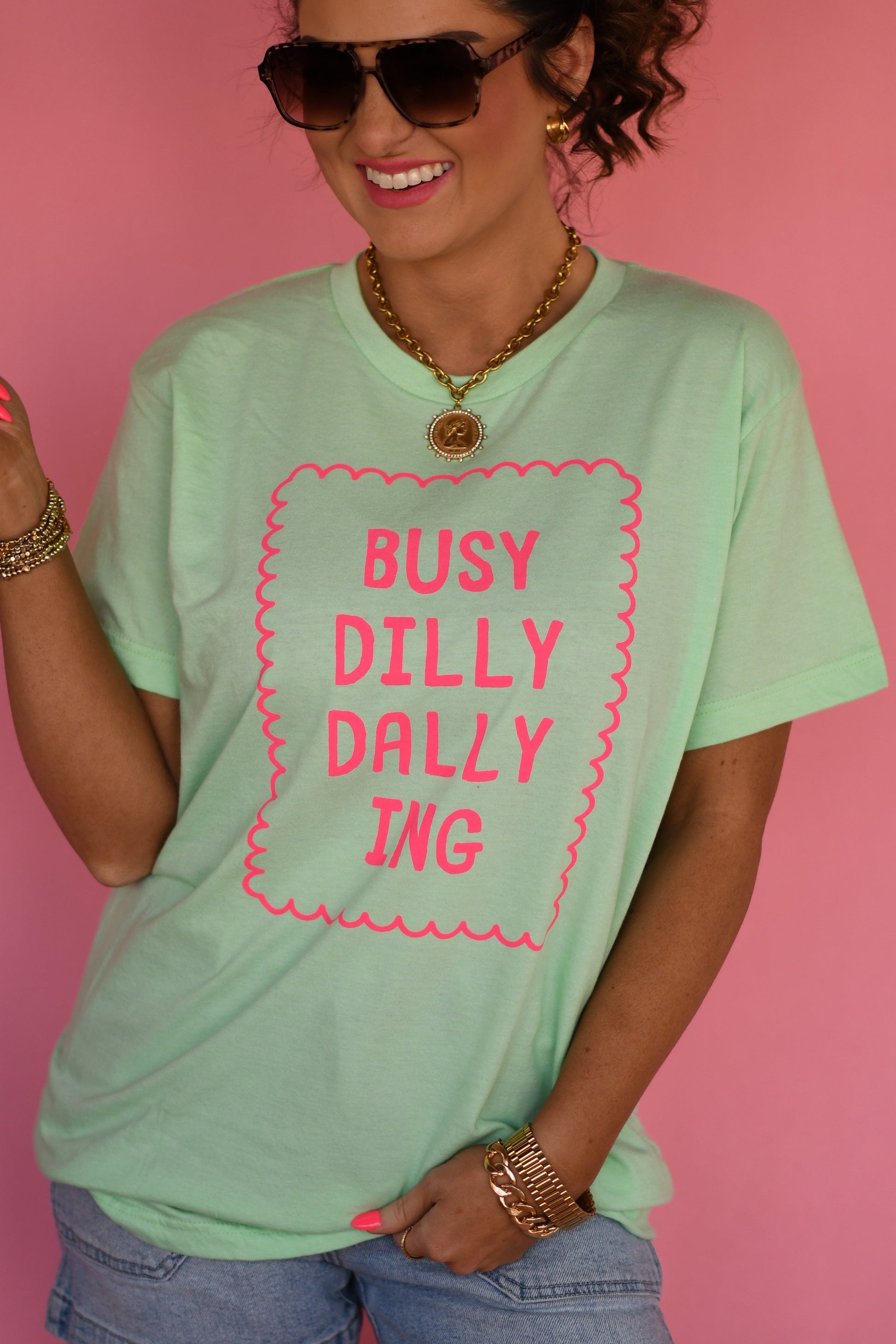 Person wearing a light green t-shirt with pink text against a pink background