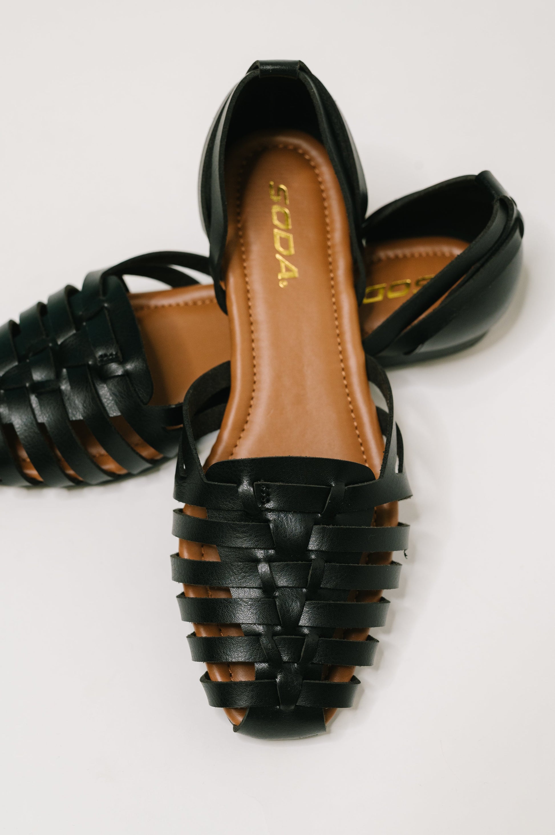 Black strappy shoes with brown insole on a white background