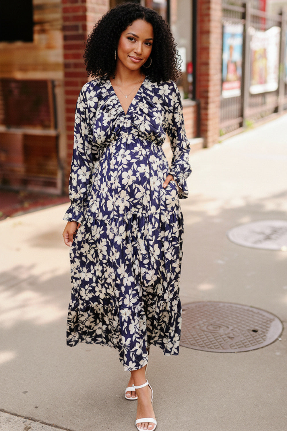 Woman wearing a blue floral dress on a city street.