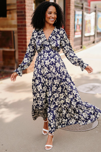 Woman wearing a blue floral dress walking outdoors.