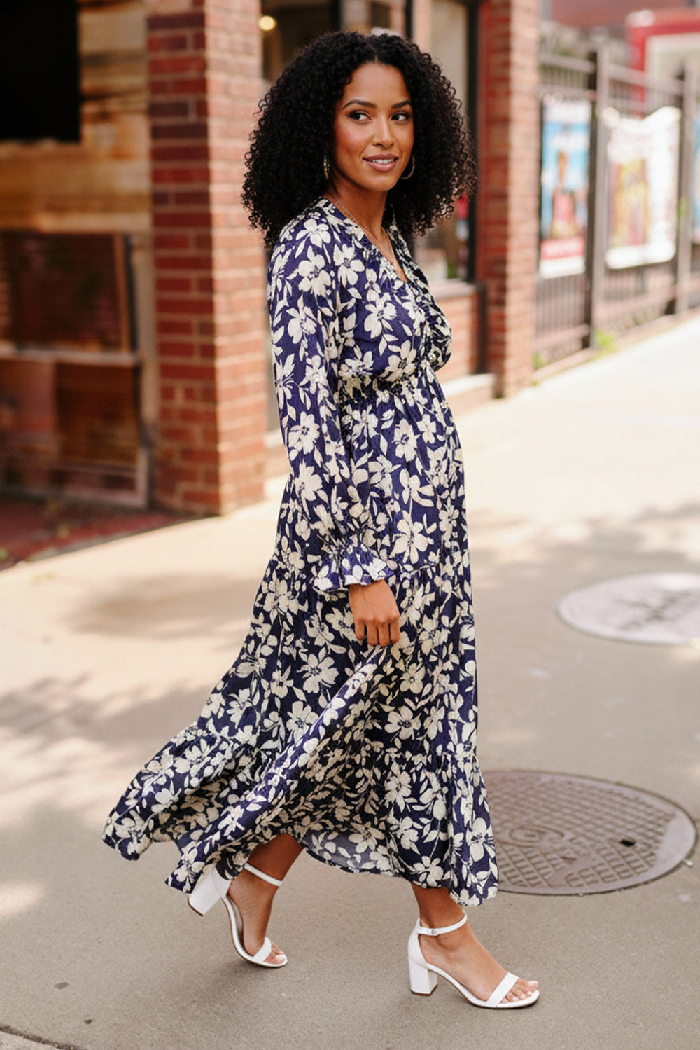 Woman wearing a blue floral dress on a city street.
