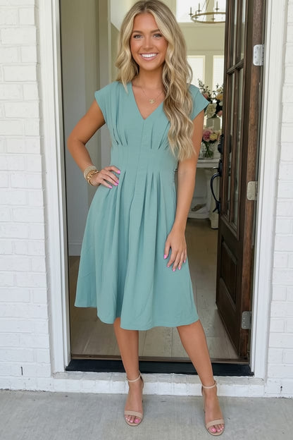 Woman wearing a light blue dress standing in a doorway.