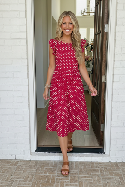 Woman wearing a pink polka dot dress standing in a doorway.