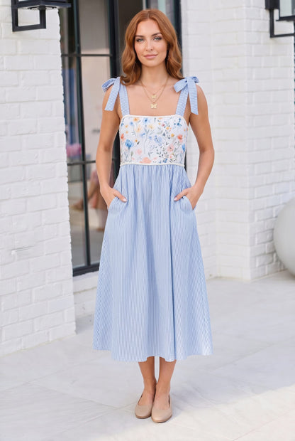 Woman wearing a light blue dress with floral top in an urban setting