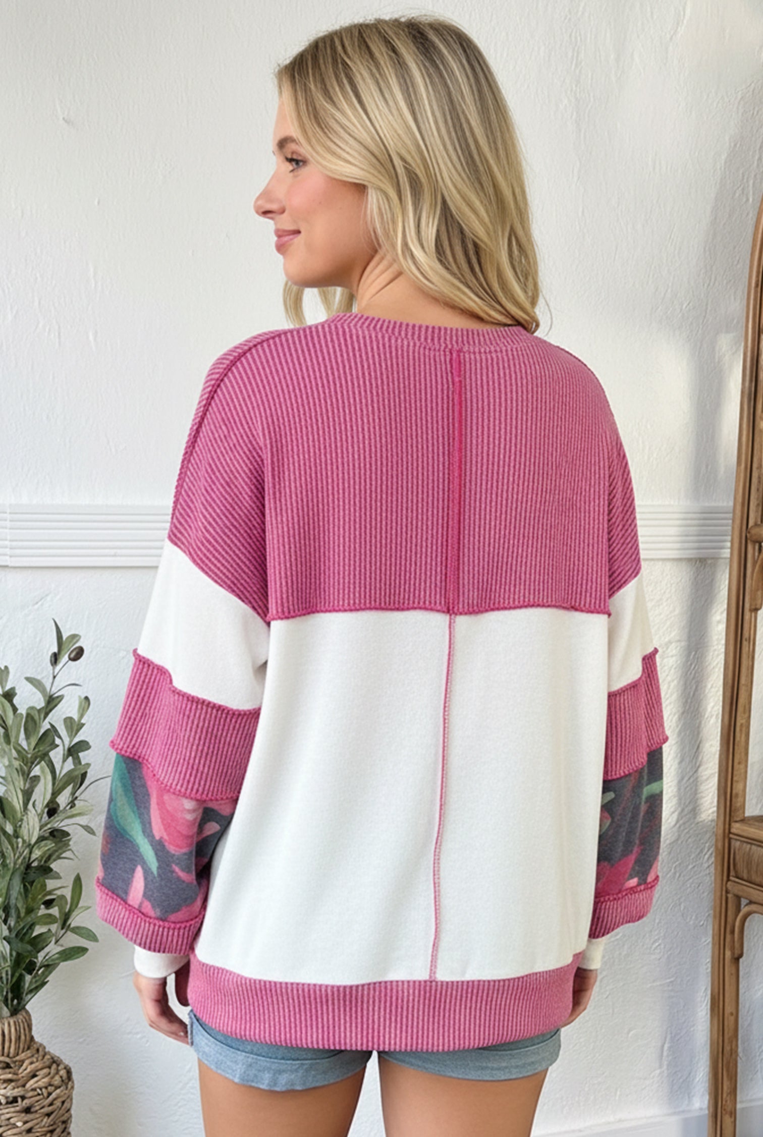 Woman wearing a pink and white sweater with abstract patterns.