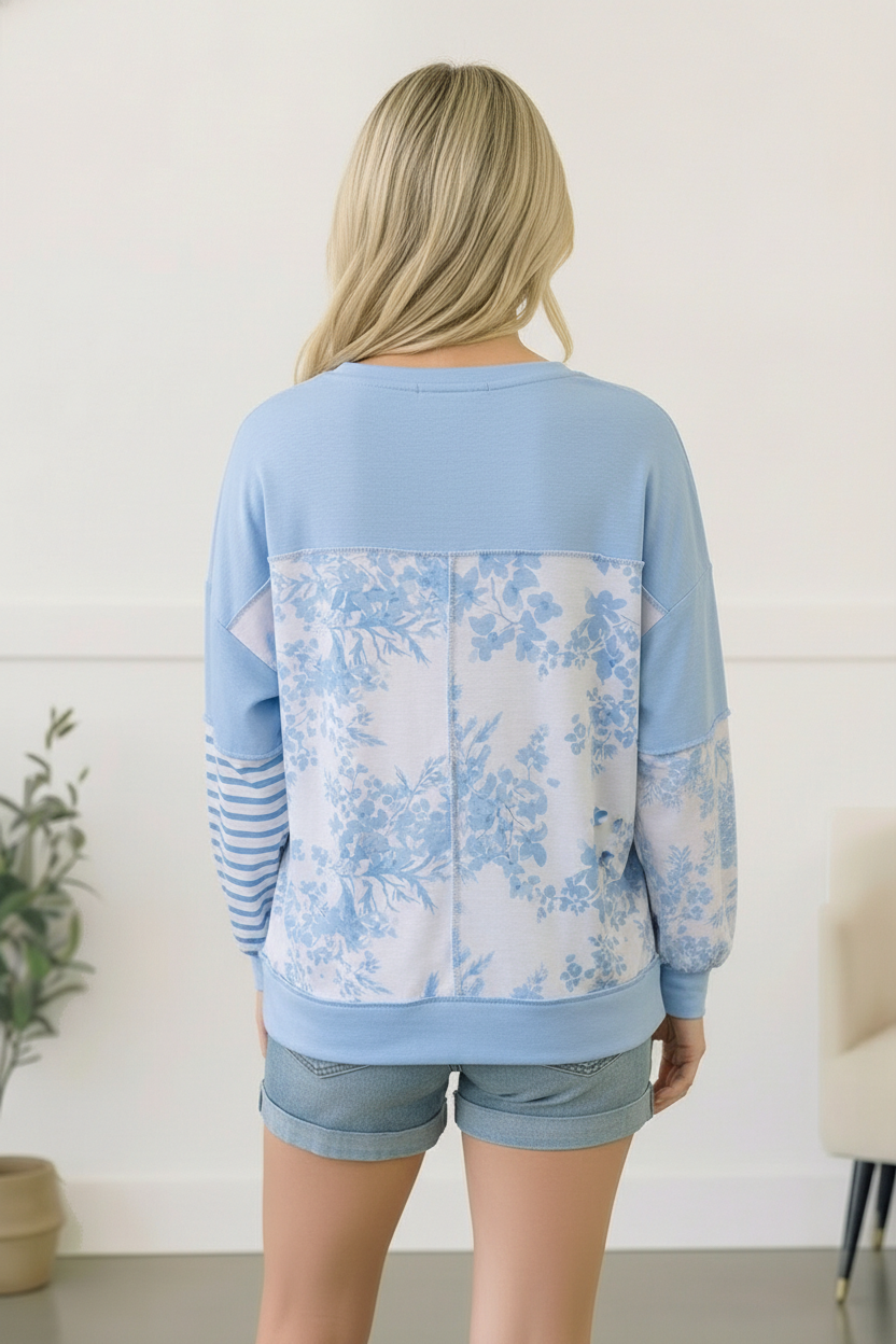 Woman wearing a light blue floral-patterned sweatshirt with a white background