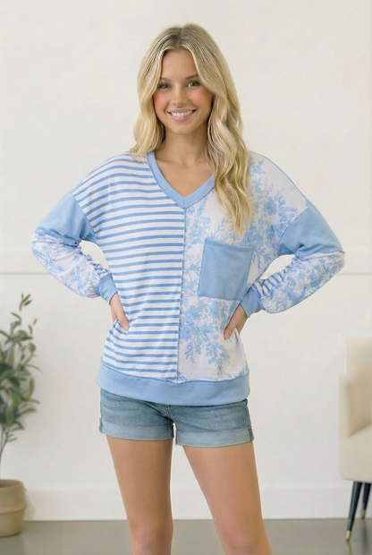 Woman wearing a blue and white striped shirt with floral patterns and denim shorts indoors.