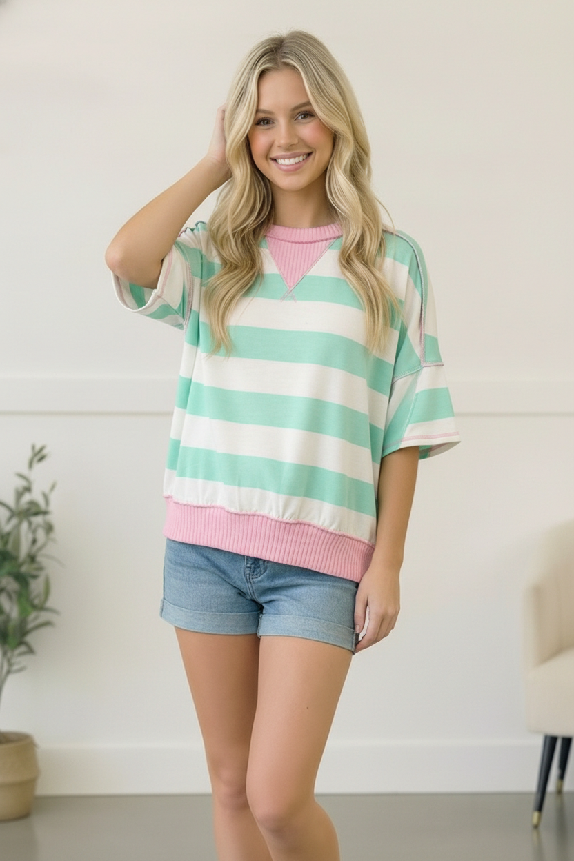 Woman wearing a colorful striped shirt and shorts indoors.