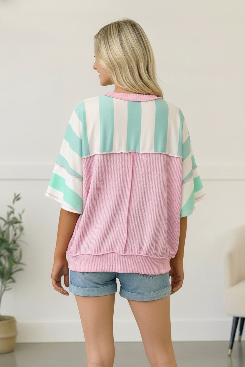 Woman wearing a striped sweater with pink and green colors, standing indoors.