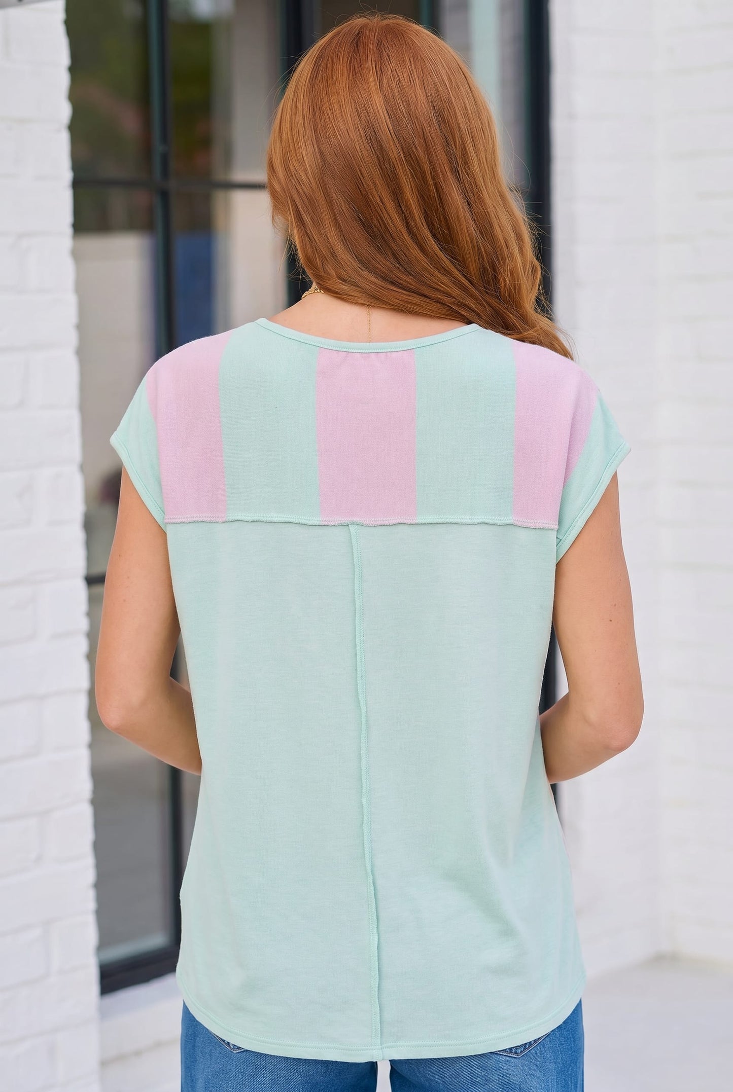 Woman wearing a light green top with pink stripes in an outdoor setting.