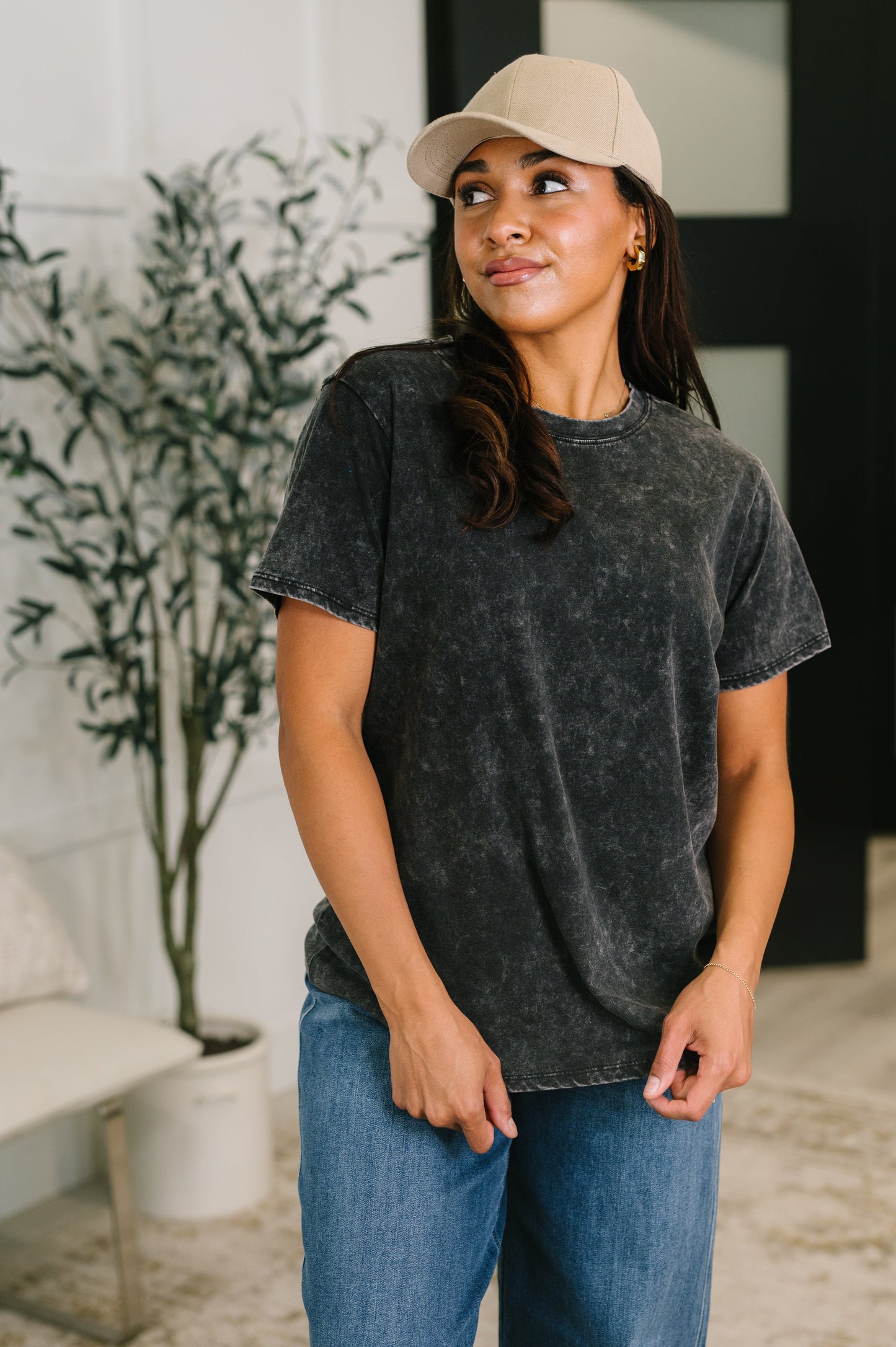 Woman wearing a black t-shirt and beige cap indoors