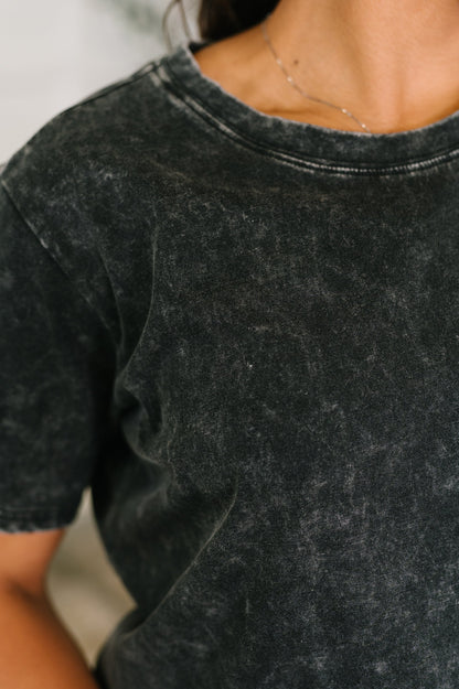 Close-up of a person wearing a dark gray t-shirt with a blurred background