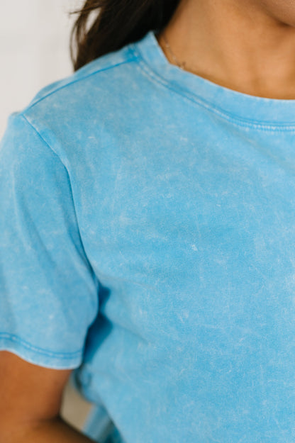 Close-up of a person wearing a light blue t-shirt with a blurred background