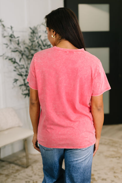 Person wearing a pink t-shirt and blue jeans in an indoor setting