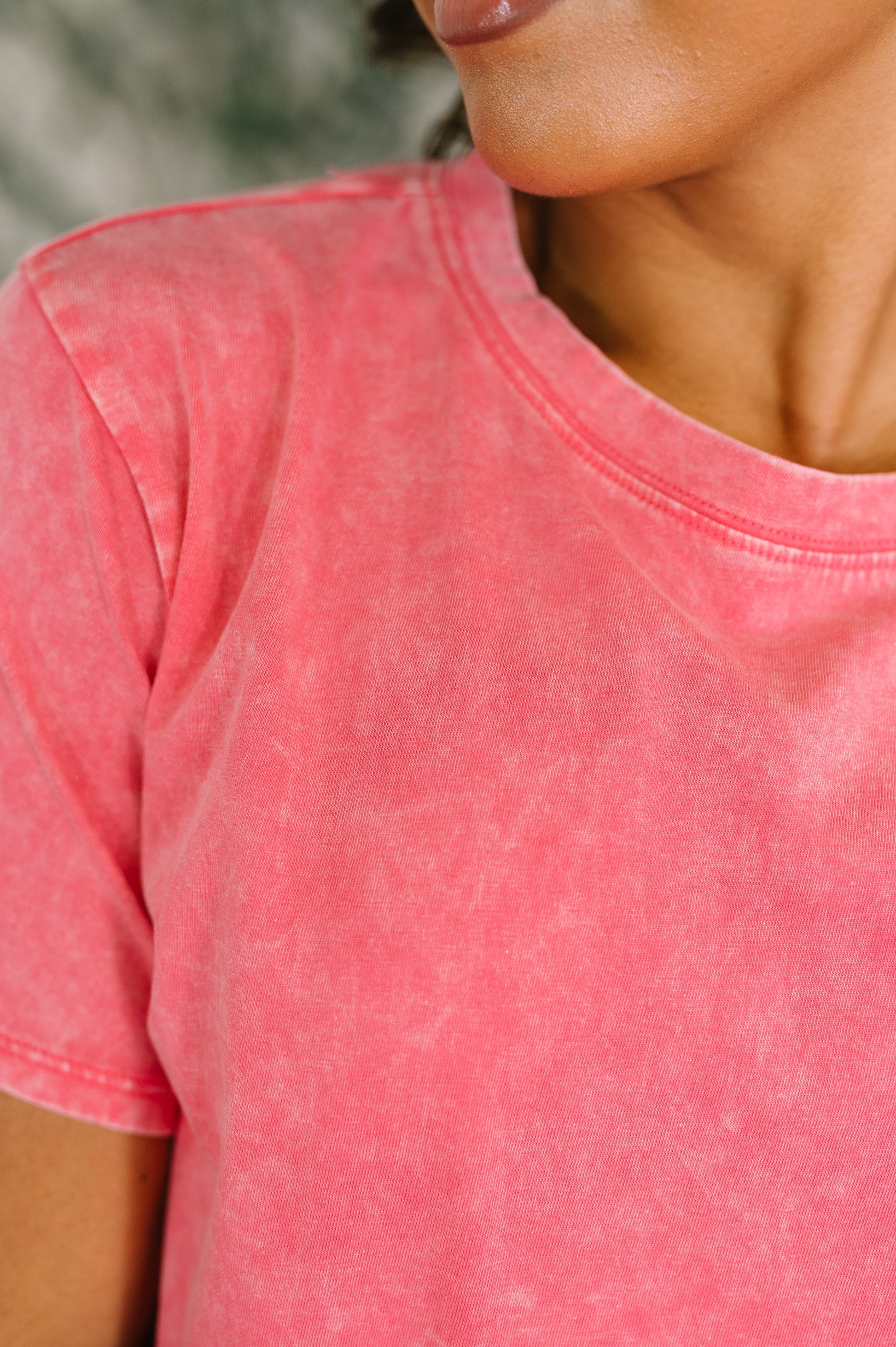 Close-up of a person wearing a pink t-shirt with a blurred background