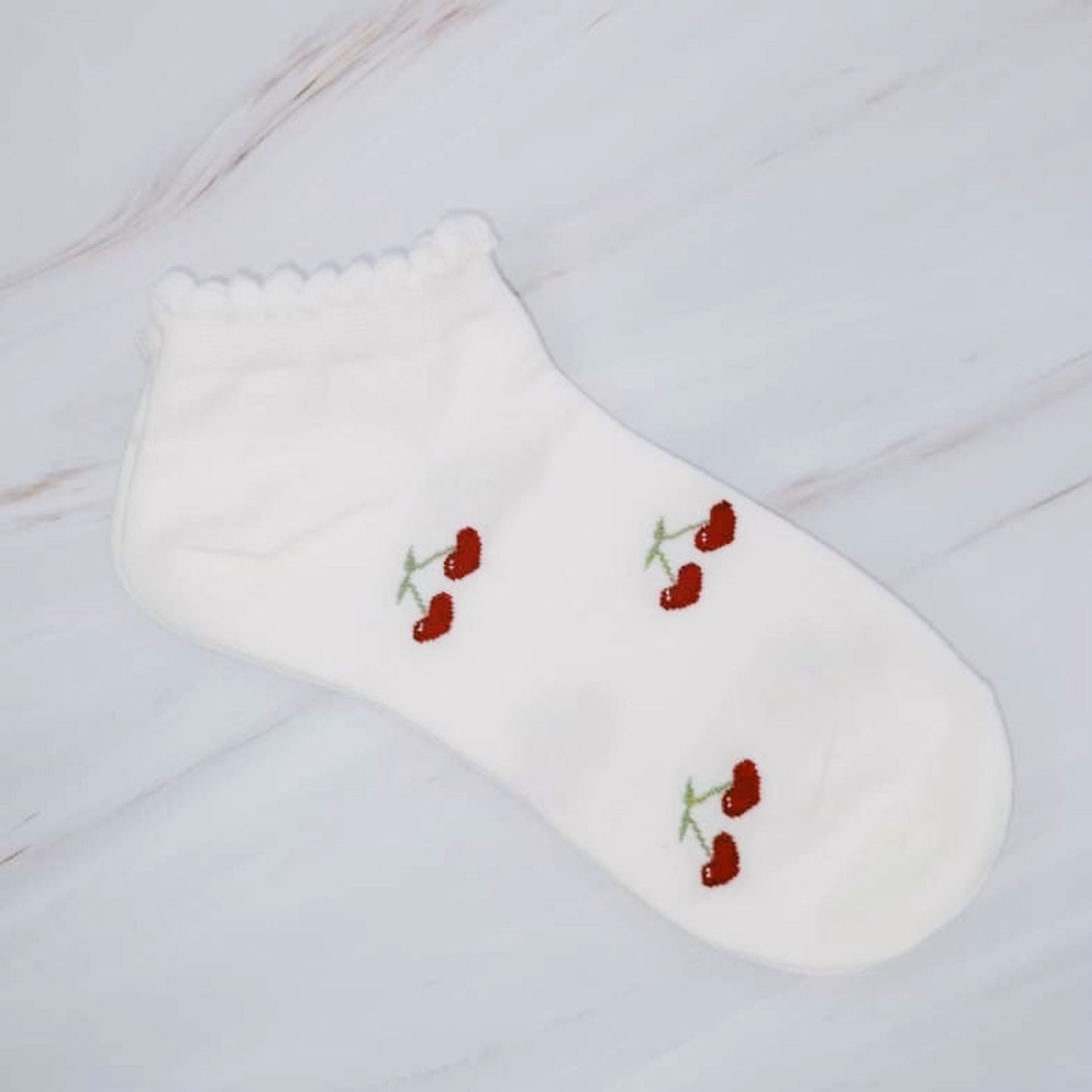 White sock with red floral embroidery on a light wooden surface