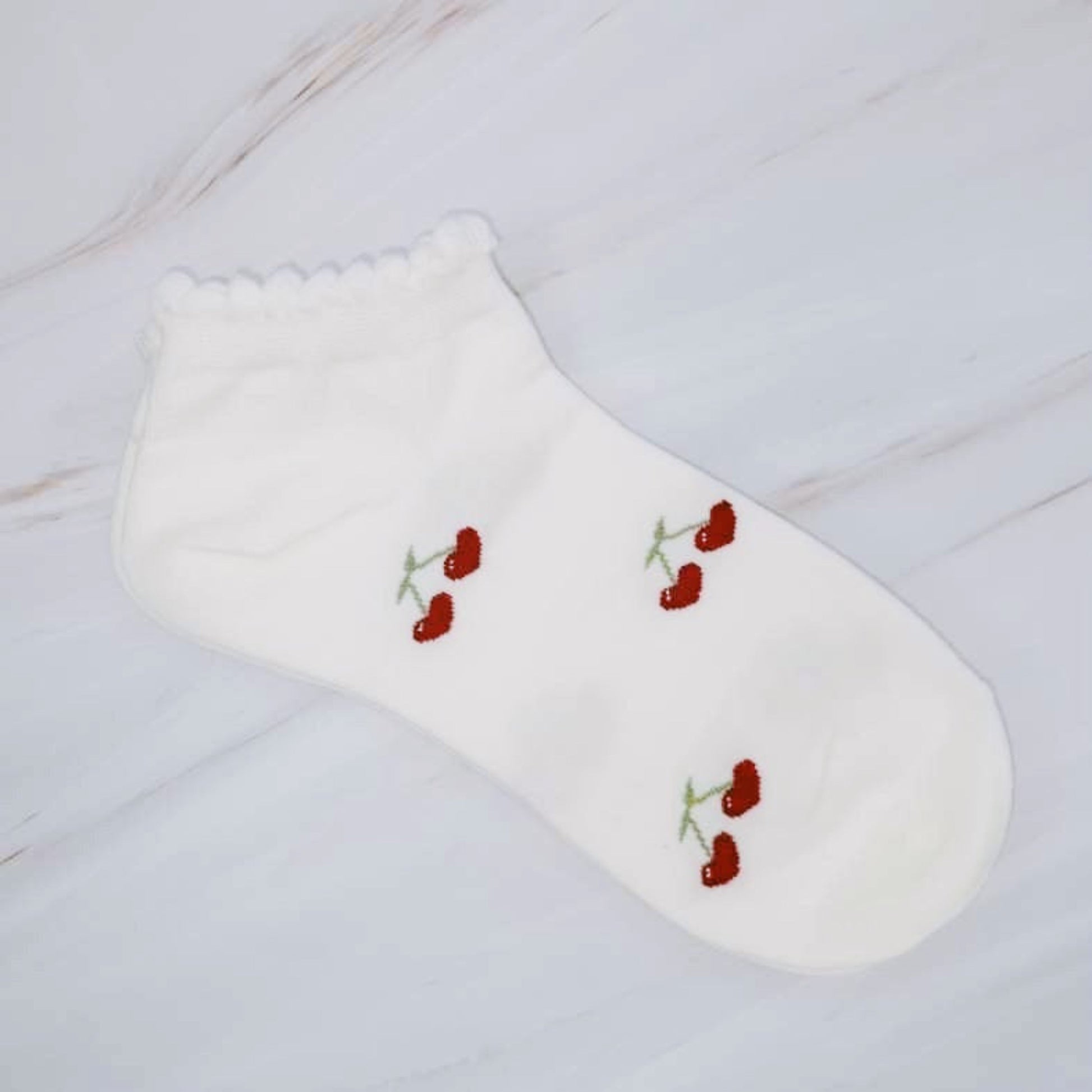 White sock with red floral embroidery on a light wooden surface