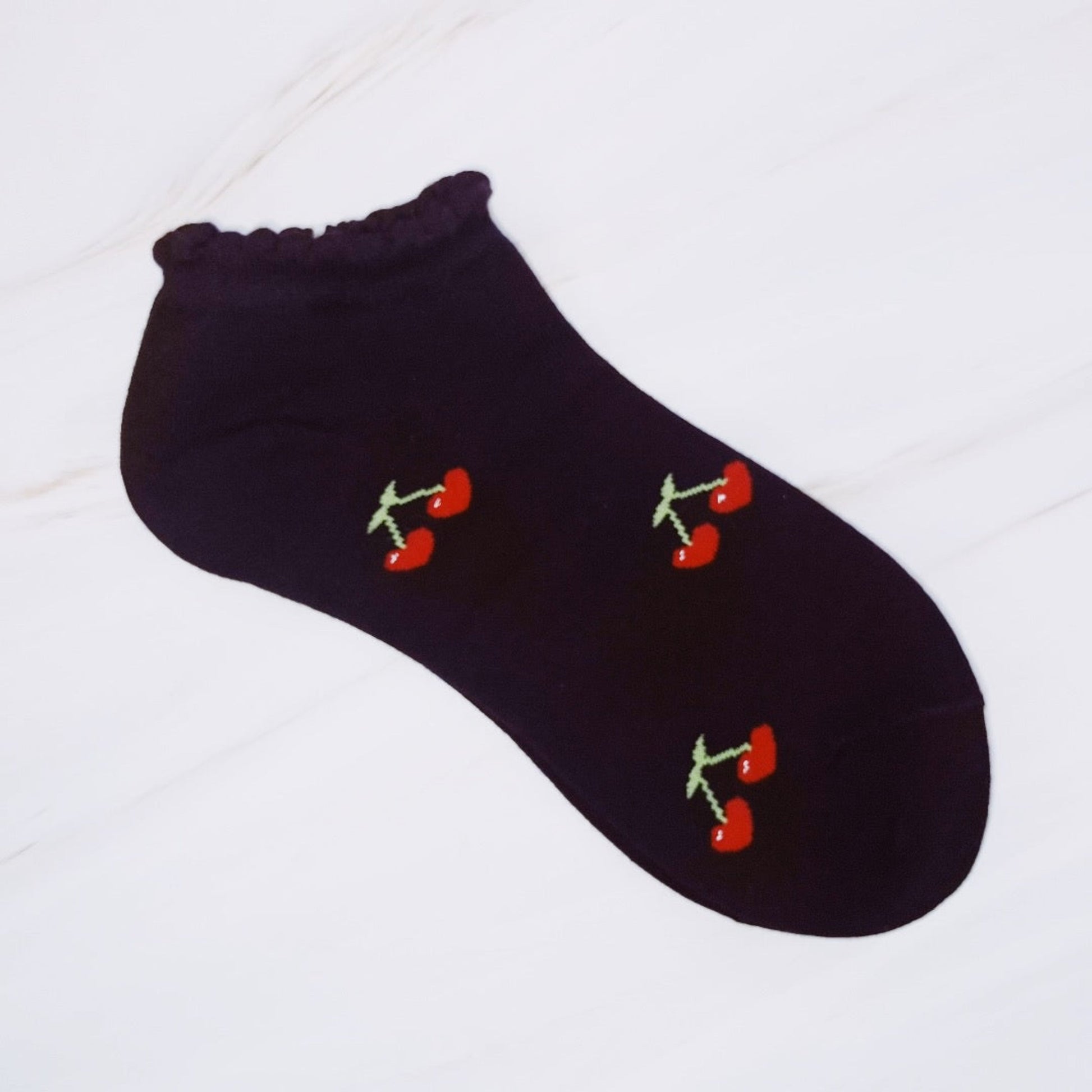 Black ankle sock with cherry designs on a white background