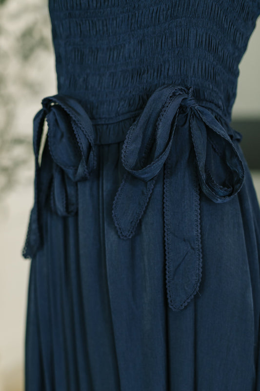 Navy blue dress with bow details on a blurred background