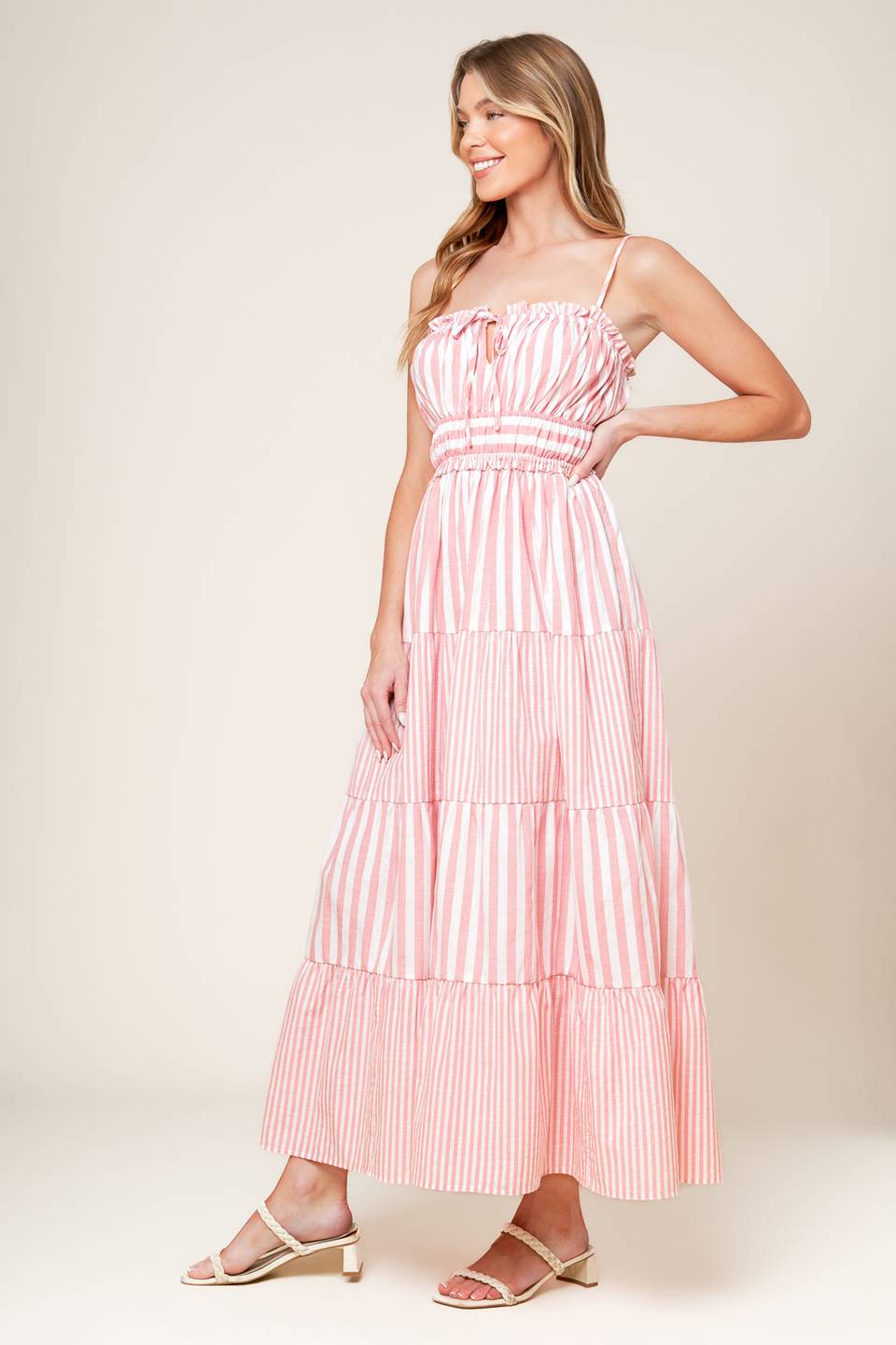 A pink and white striped dress with tiered skirt and ruffle detailing