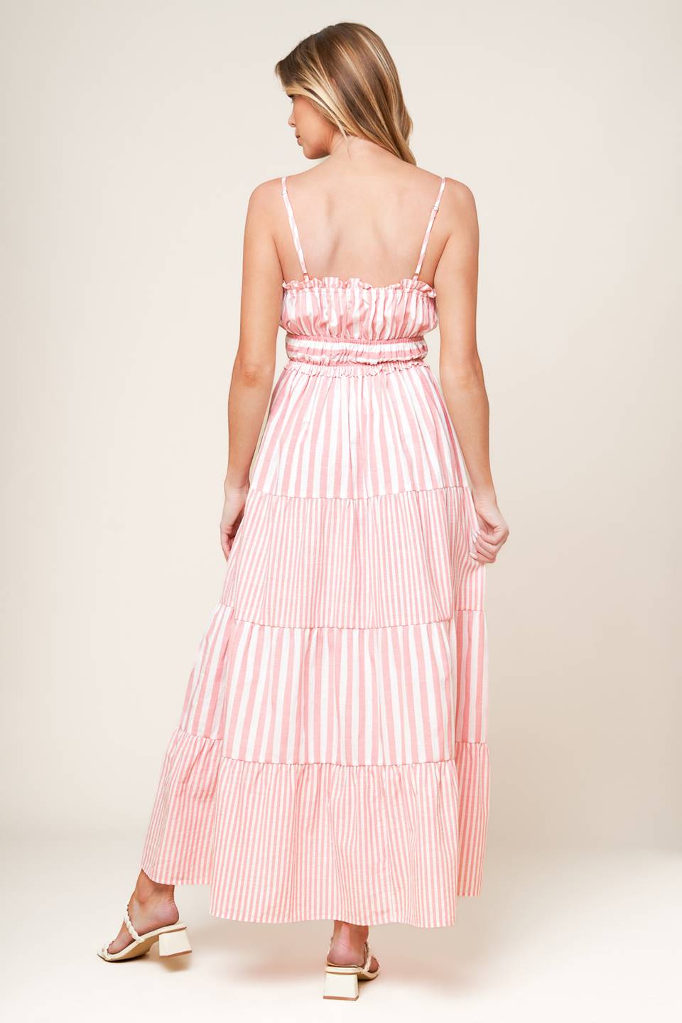 A pink and white striped dress with tiered skirt and ruffle detailing