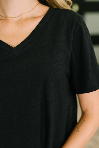 Person wearing a black t-shirt with a blurred background