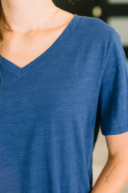 Close-up of a person wearing a blue V-neck shirt with a blurred background