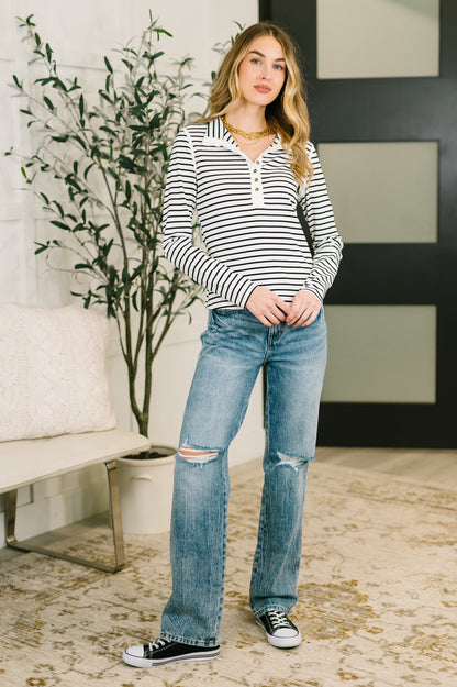 Woman wearing a striped shirt and jeans standing in a living room.