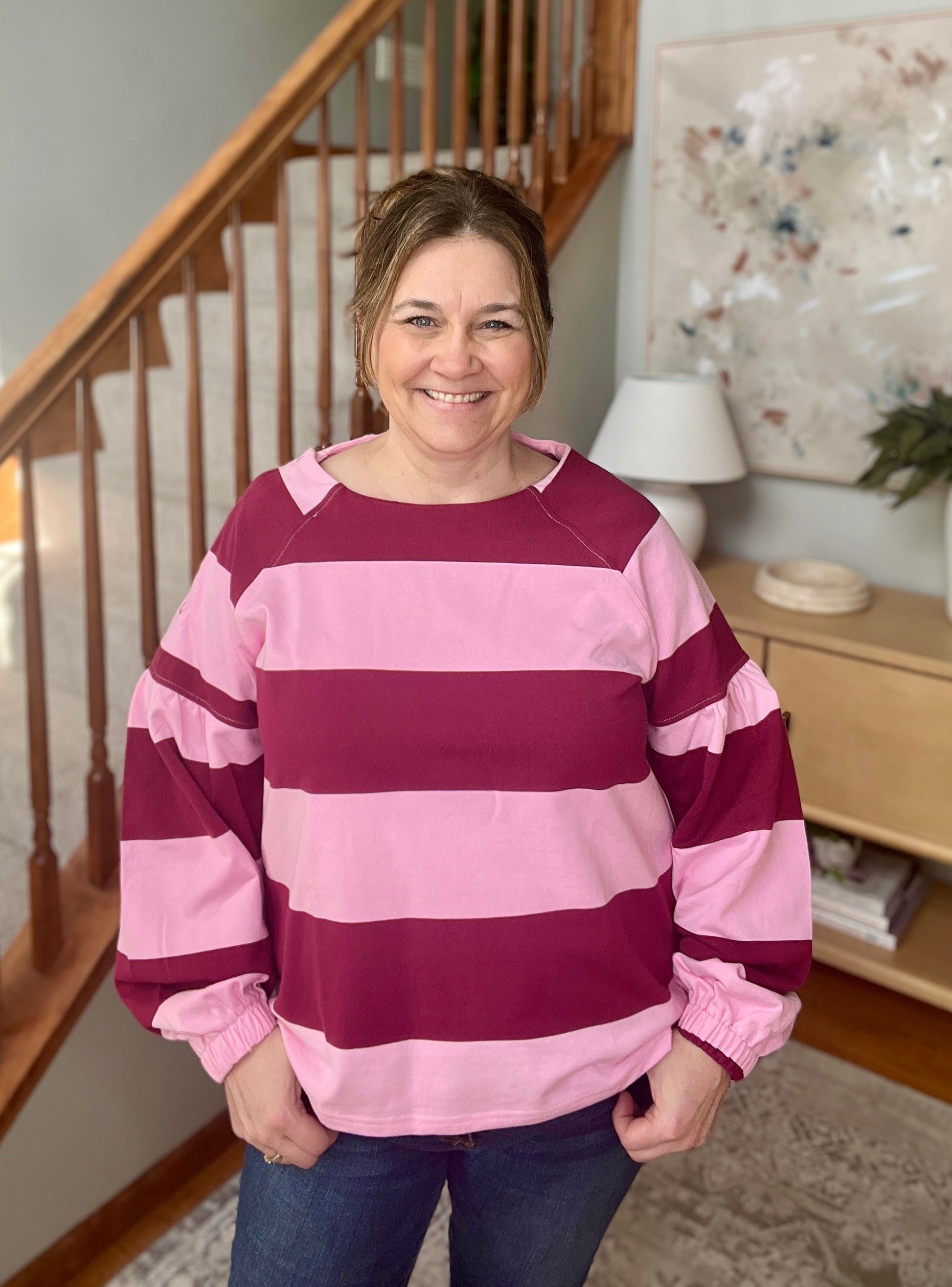 Person wearing a pink and purple striped sweater in a home setting