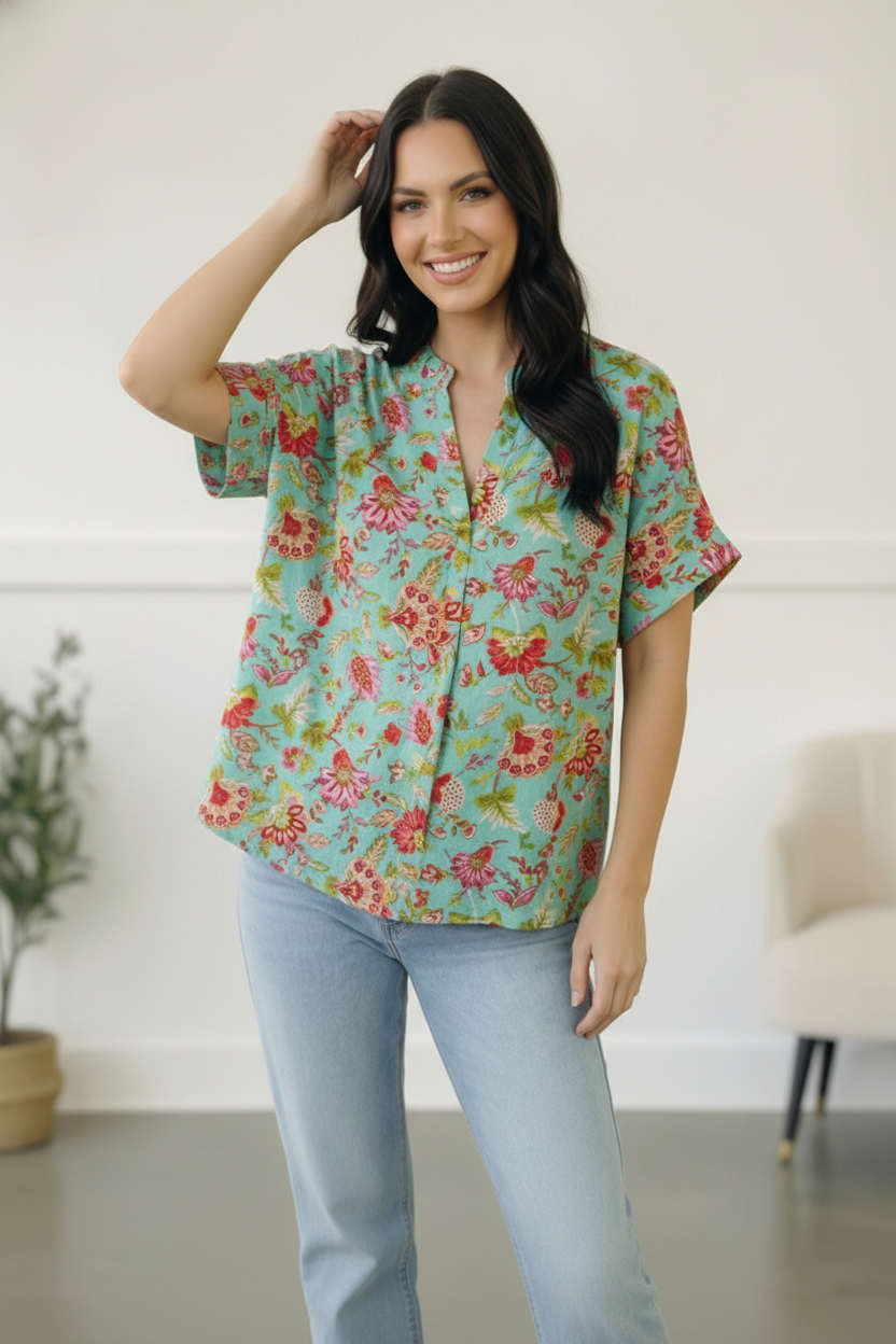 Woman wearing a floral blouse and light blue jeans indoors.