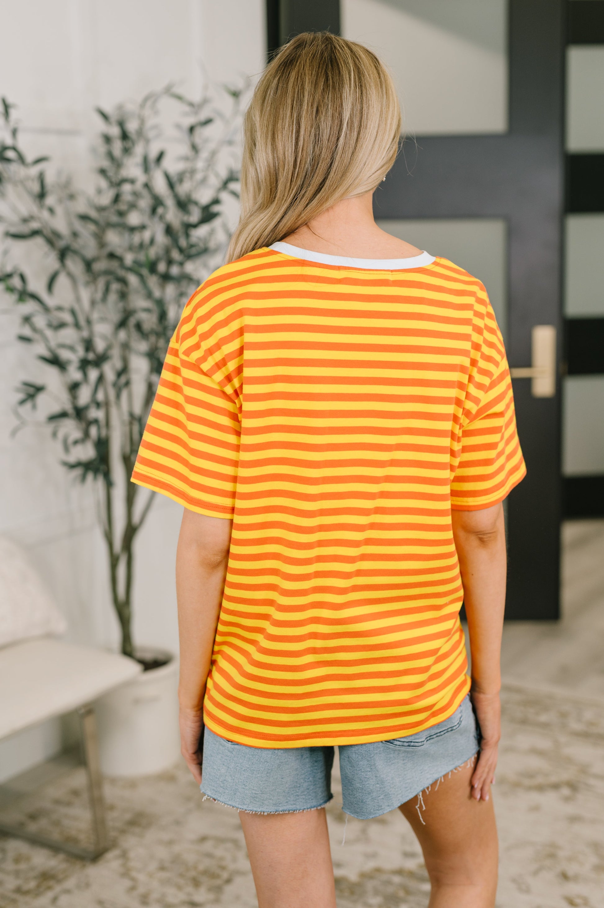 Person wearing a yellow and orange striped shirt in an indoor setting