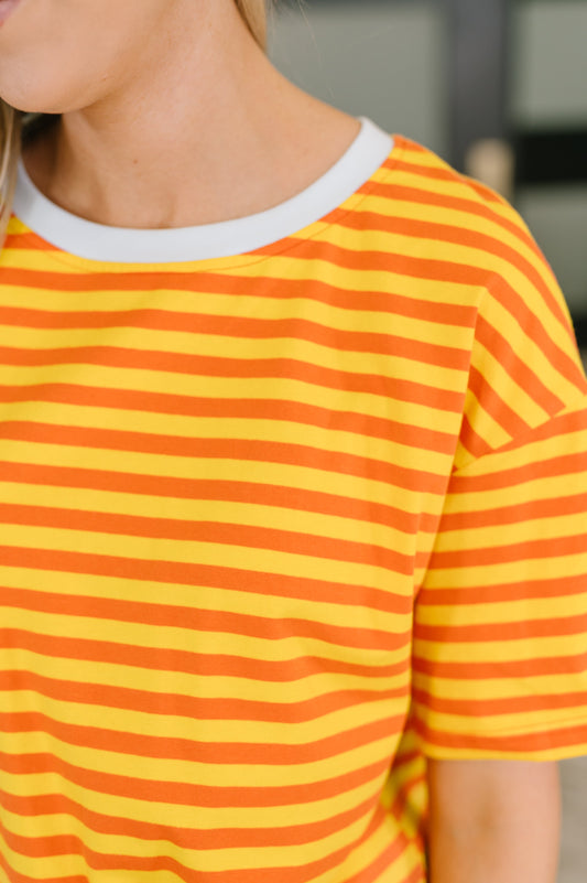 Person wearing a yellow and orange striped shirt with a blurred background