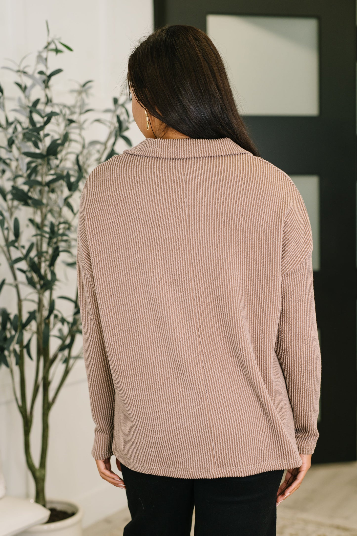 Person wearing a beige ribbed sweater in an indoor setting