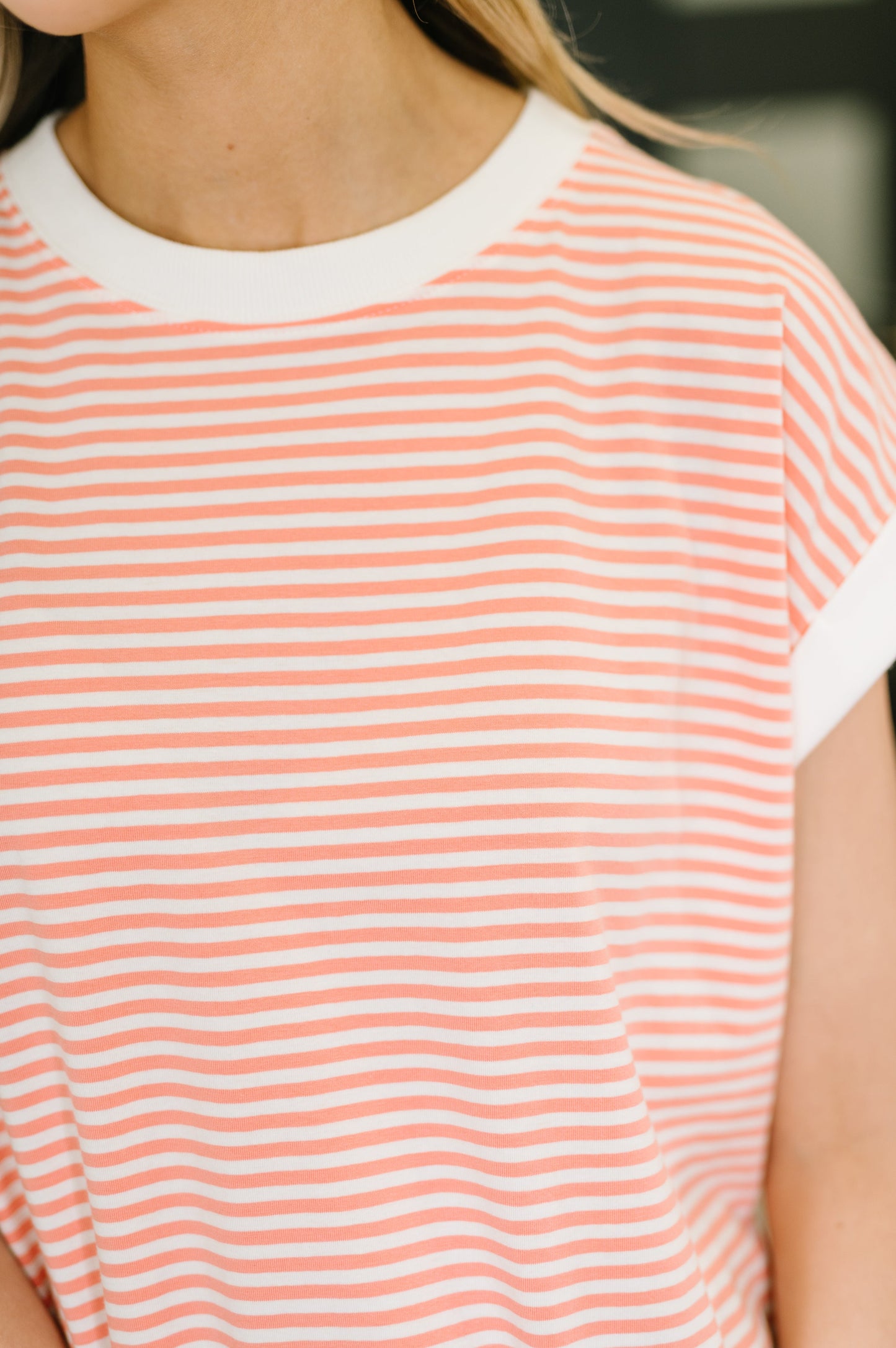 Close-up of a person wearing a coral striped shirt.