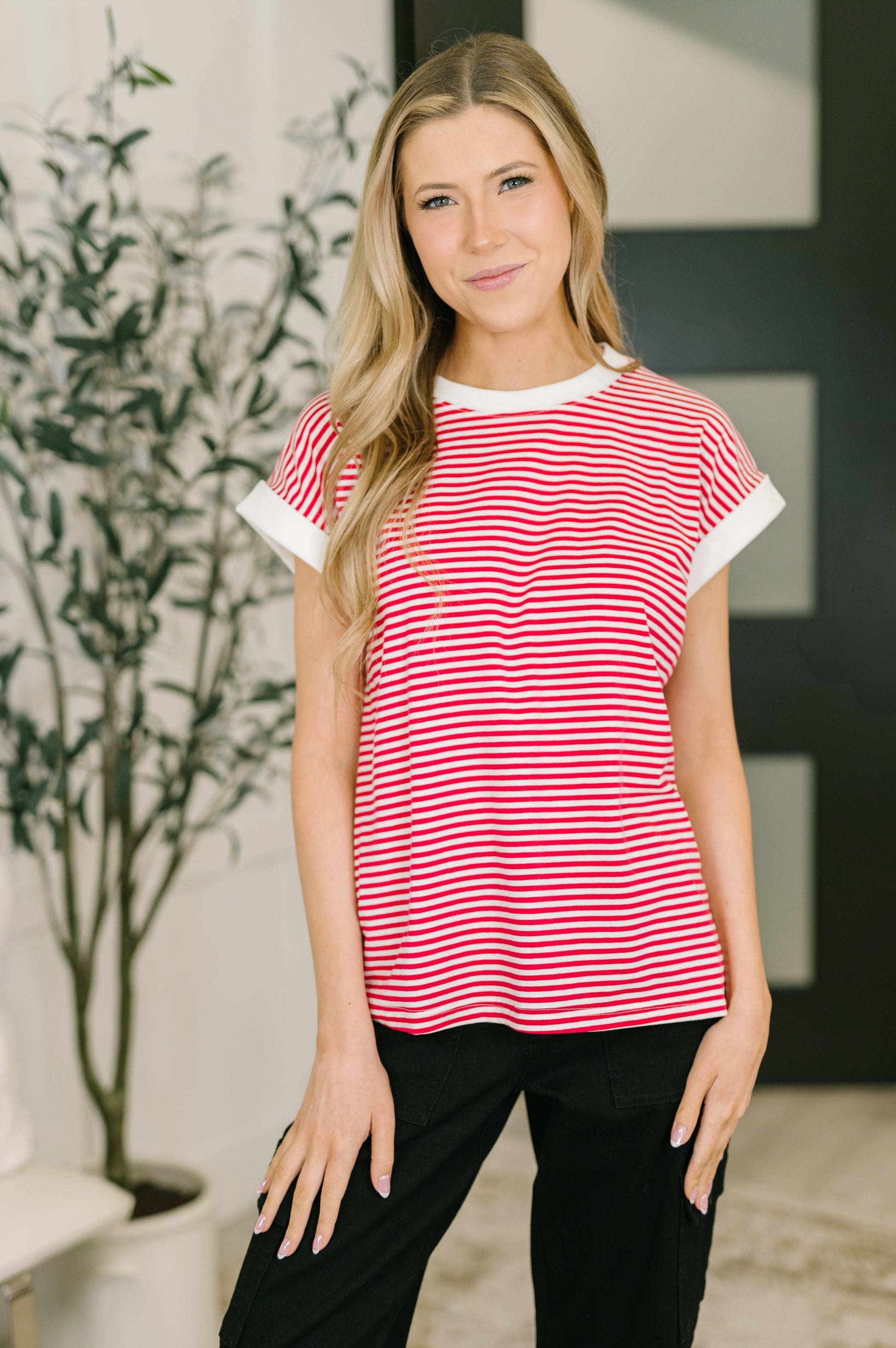 Woman wearing a red and white striped shirt with black pants indoors.