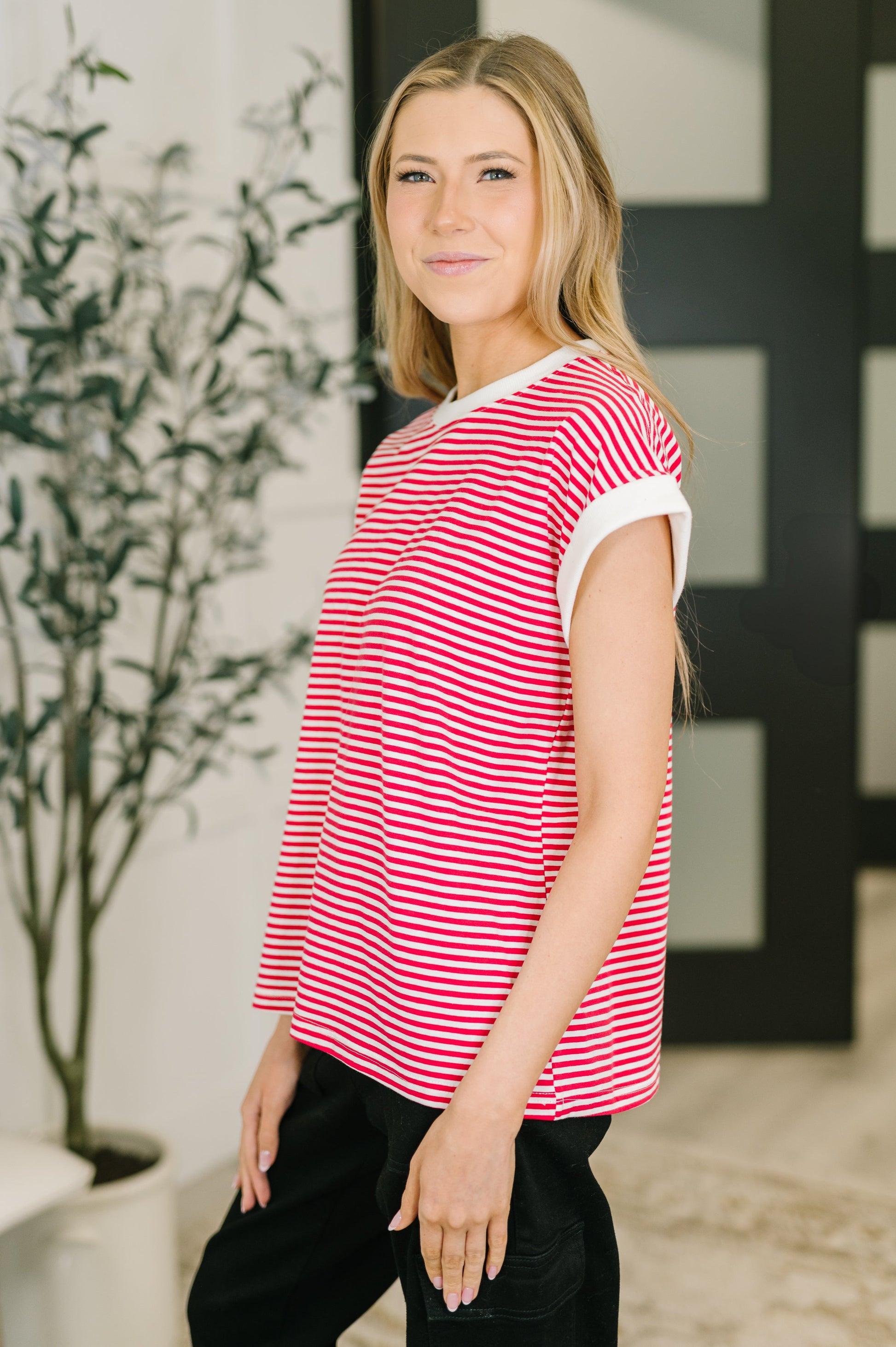 Woman wearing a red and white striped shirt in an indoor setting with a plant in the background
