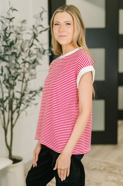 Woman wearing a red and white striped shirt in an indoor setting with a plant in the background