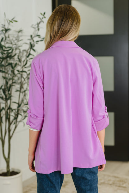Person wearing a purple jacket indoors with a plant and door in the background