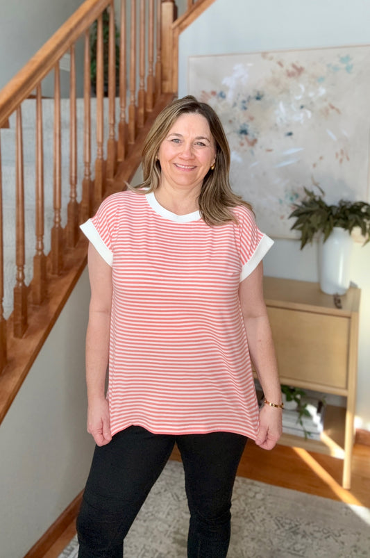 Woman wearing a red and white striped shirt standing in a home setting with a staircase.