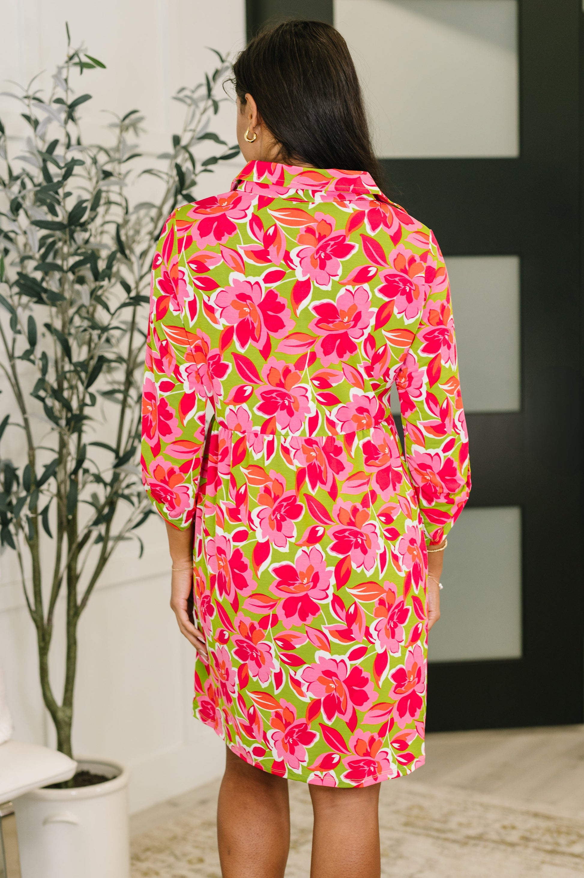 Woman wearing a colorful floral dress in an indoor setting.