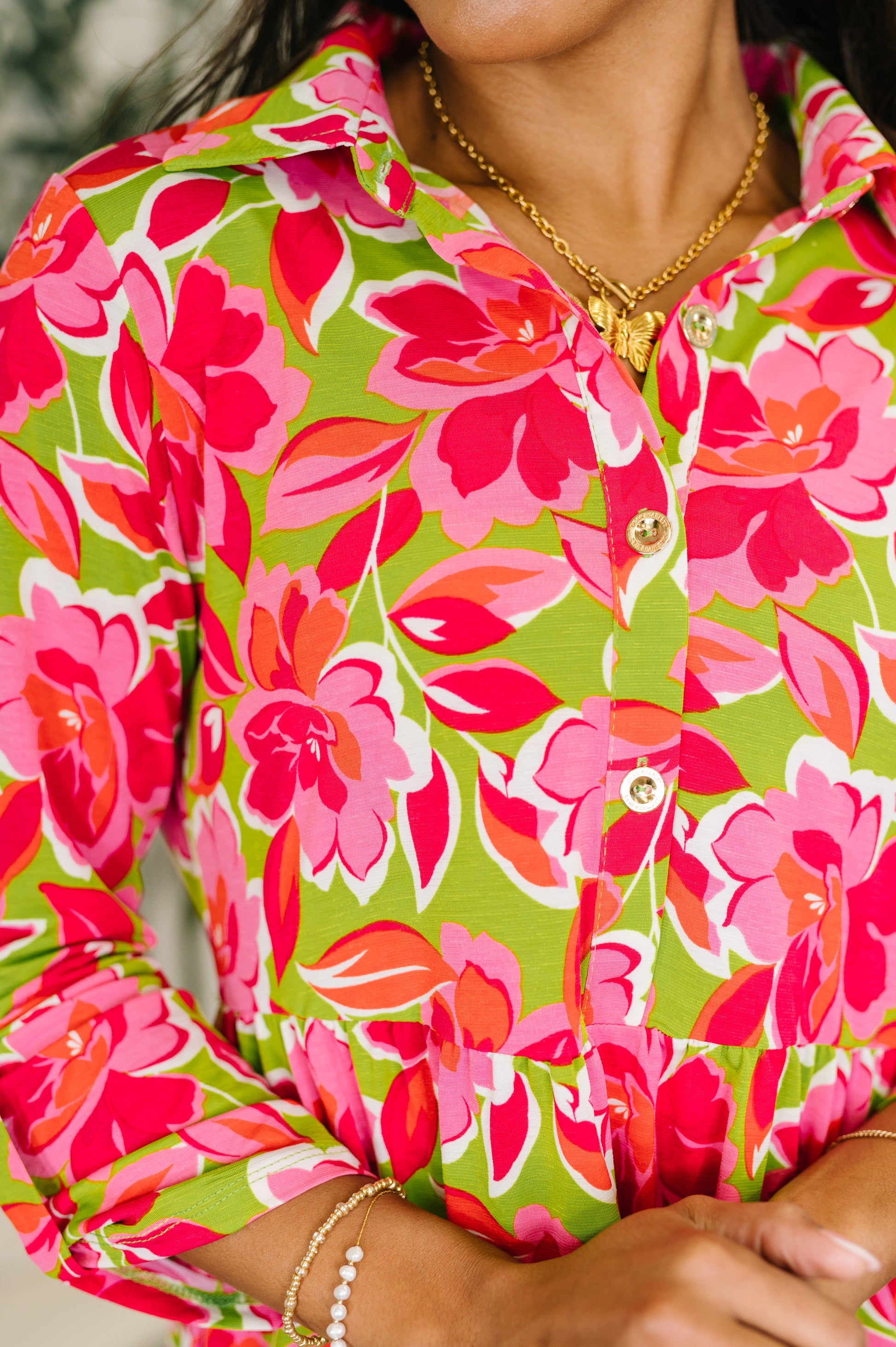 Close-up of a person wearing a colorful floral shirt with pink and green flowers.