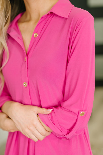 Close-up of a person wearing a bright pink dress with gold buttons.