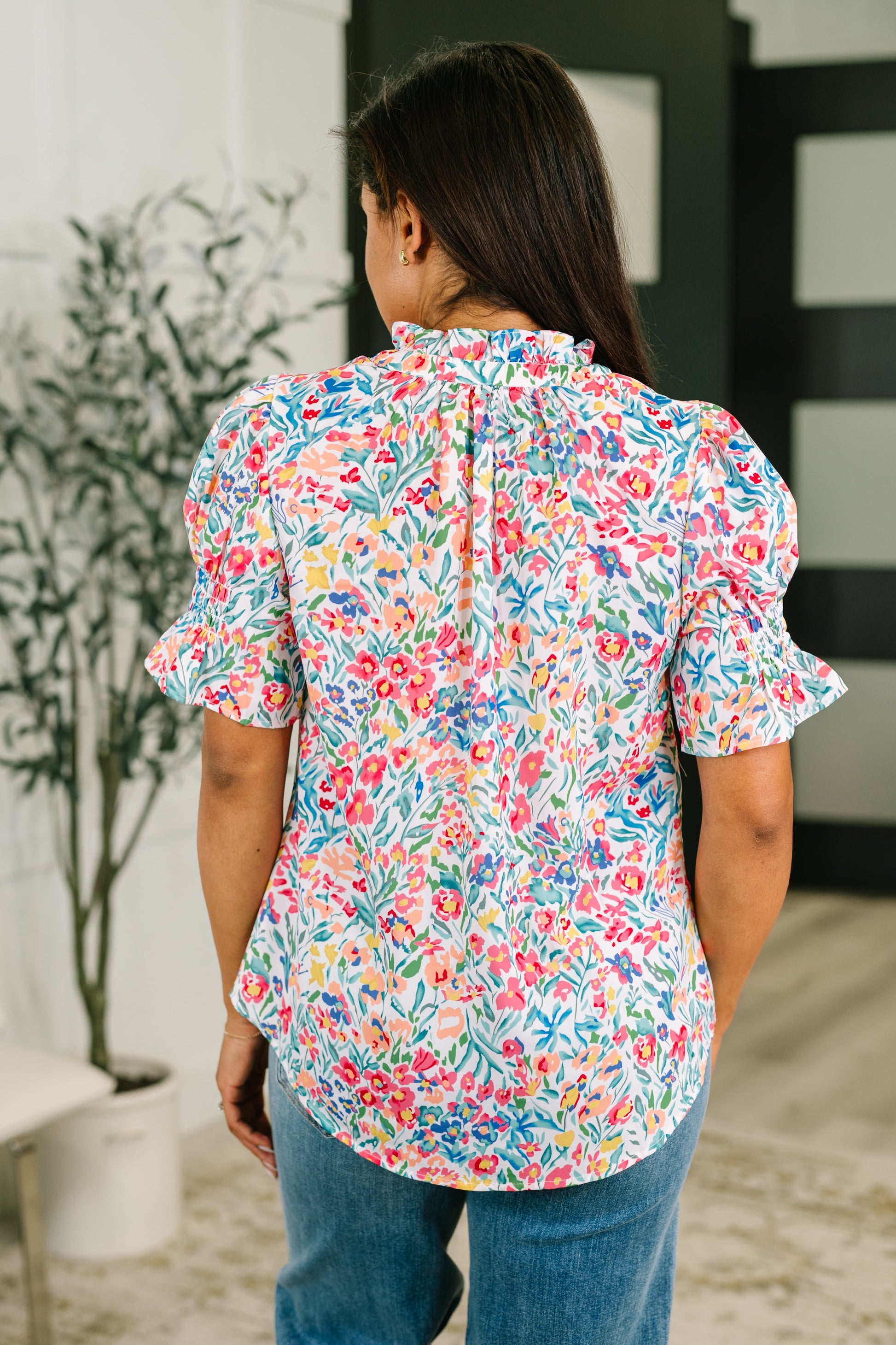 Woman wearing a colorful floral blouse in an indoor setting